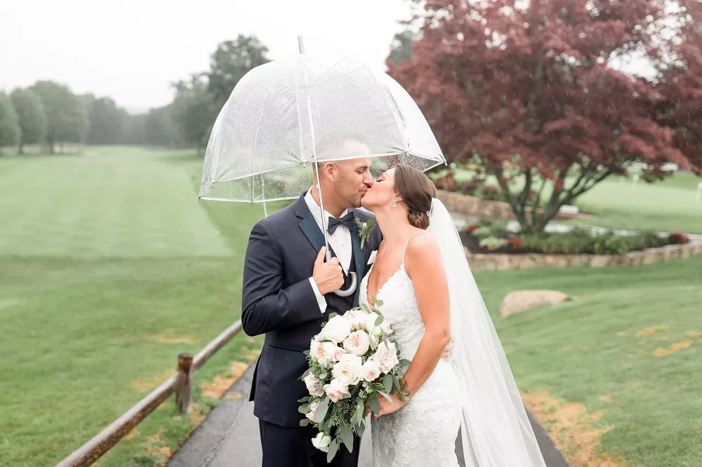 Bride and groom with umbrella taking photos in the rain at the best outdoor wedding venue in Rhode Island, Kirkbrae Country Club