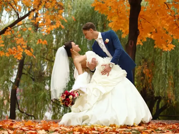 Bride and groom pose beneath orange trees, an autumn photo backdrop for Rhode Island fall foliage wedding photos at Kirkbrae Country Club