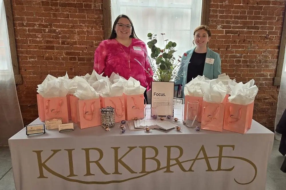 Kirkbrae staff members at a corporate event table containing bagged gifts for corporate event guests