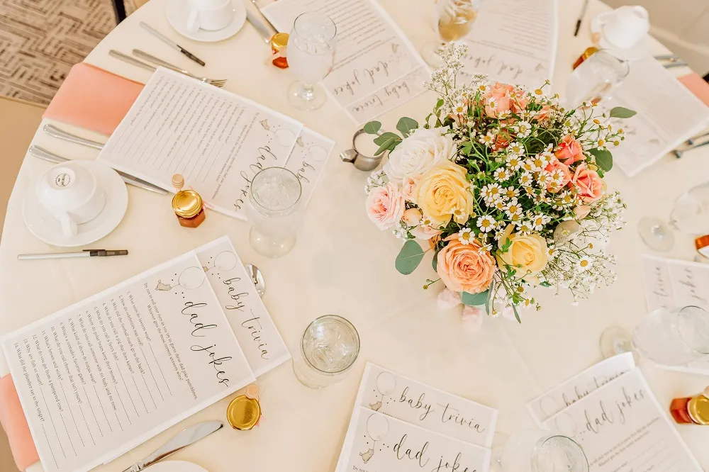 Table in the charcoal room with beautiful floral centerpiece, glassware, and cards
