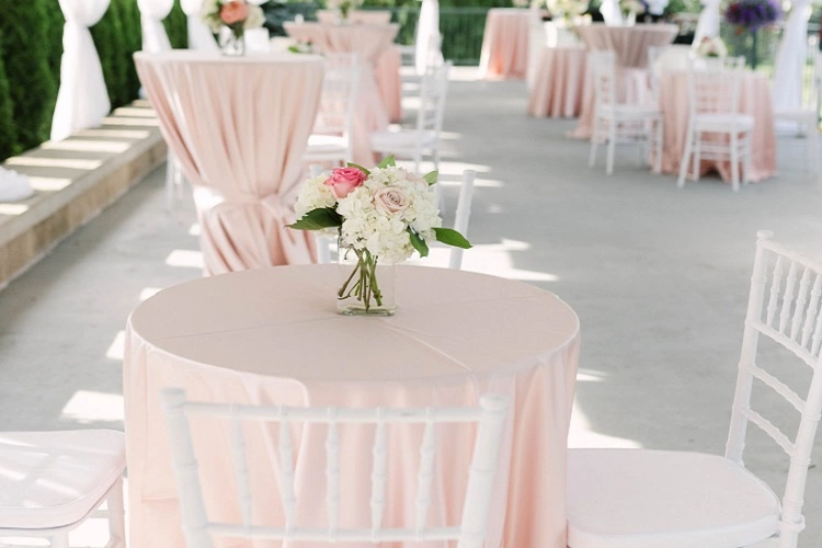 outdoor baby shower party table setup with pink table clothes and white chairs