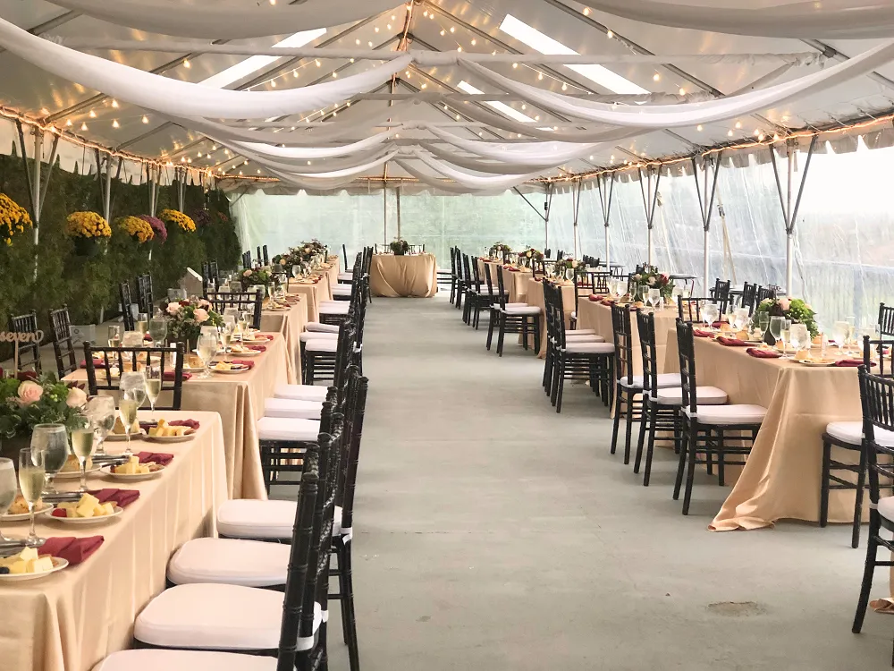 Tented patio outdoor wedding setup with chairs, floral arrangments and other decor