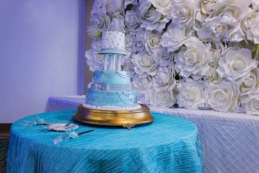 Quinceanera history and traditions celebrated with an elegant blue cake and white rose backdrop at Kirkbrae Country Club