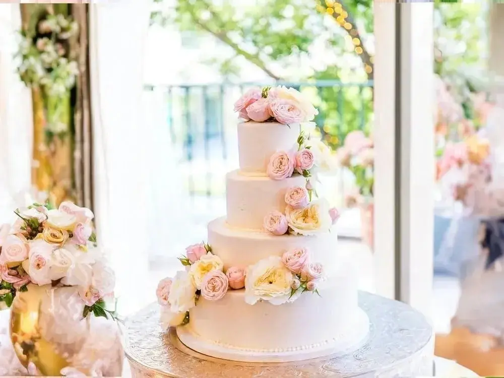 a beautiful wedding cake surrounded by flowers sitting by itself on a table