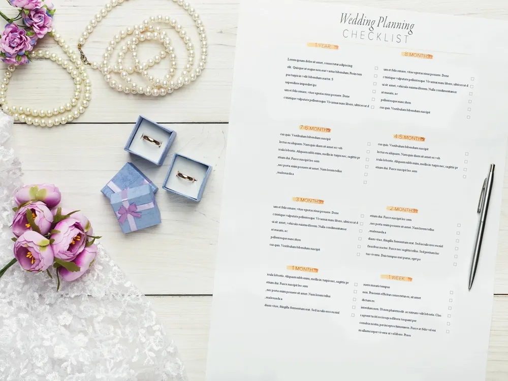 Wedding venue checklist is placed on a table surrounded by flowers, wedding bands, and necklaces